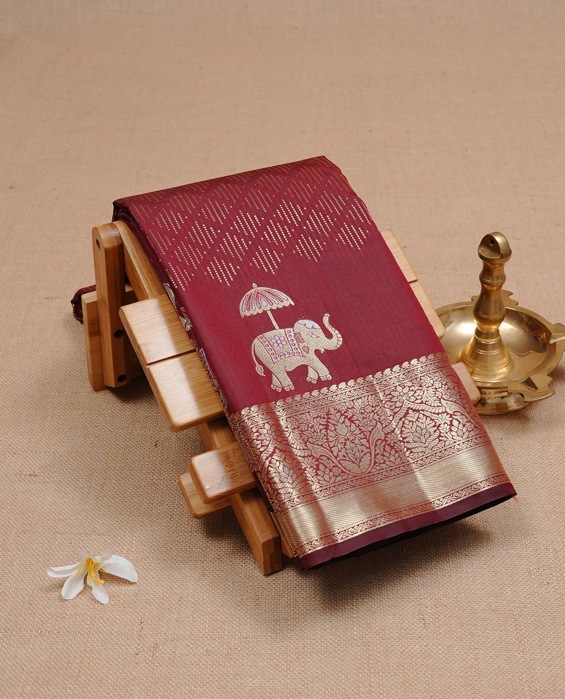 Chocolate colour semi wedding silk saree featuring Gold zari pattern on body, complemented Silver Elephant motifs & gold zari border, paired with matching blouse piece.