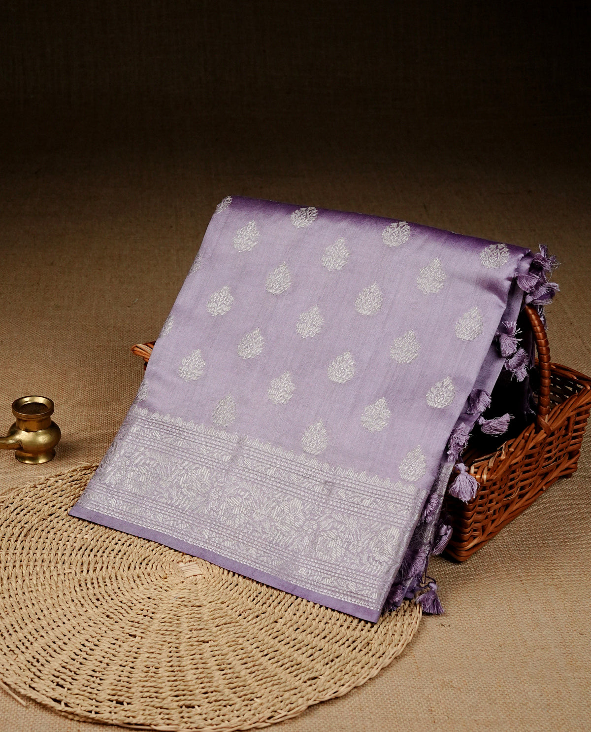 Lavender colour Banaras saree featuring Silver zari buttas on body, complemented by zari pattern on self colour border, comes with matching blouse piece.