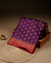 Purple colour banaras saree featuring Gold zari buttas on body, complemented by contrast Maroon colour with simple zari border, comes with matching blouse piece.
