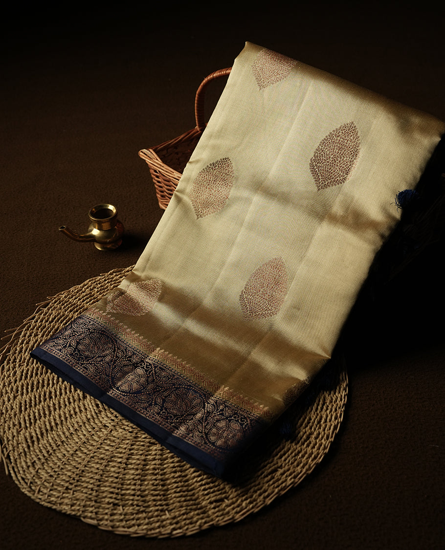 Cream Beige Colour Banaras Soft Silk Saree with Gold Zari Oval Mandala Buttas, Intricate Multi-Layered Decorative Pallu Border, Grand Pallu with Ornate Circular and Foliate Motifs in Navy Blue and Gold Tones, and Matching Navy Blue Blouse