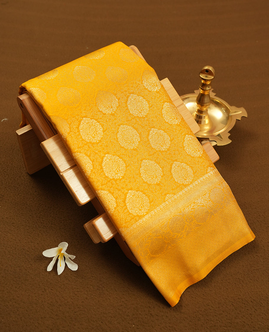 Yellow colour semi silk brocade saree featuring intricate Gold butta patterns across the body, complemented by a rich self colour woven border and pallu, paired with a matching blouse.