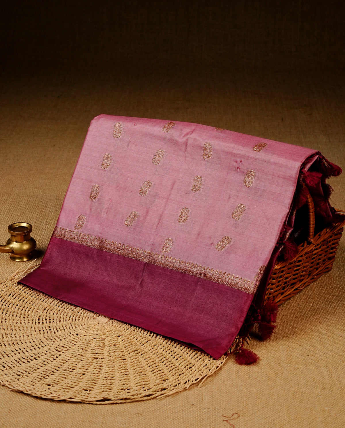 Pink colour banaras silk saree featuring Gold zari buttas on body, complemented by contrast Maroon colour border, comes with matching blouse piece.
