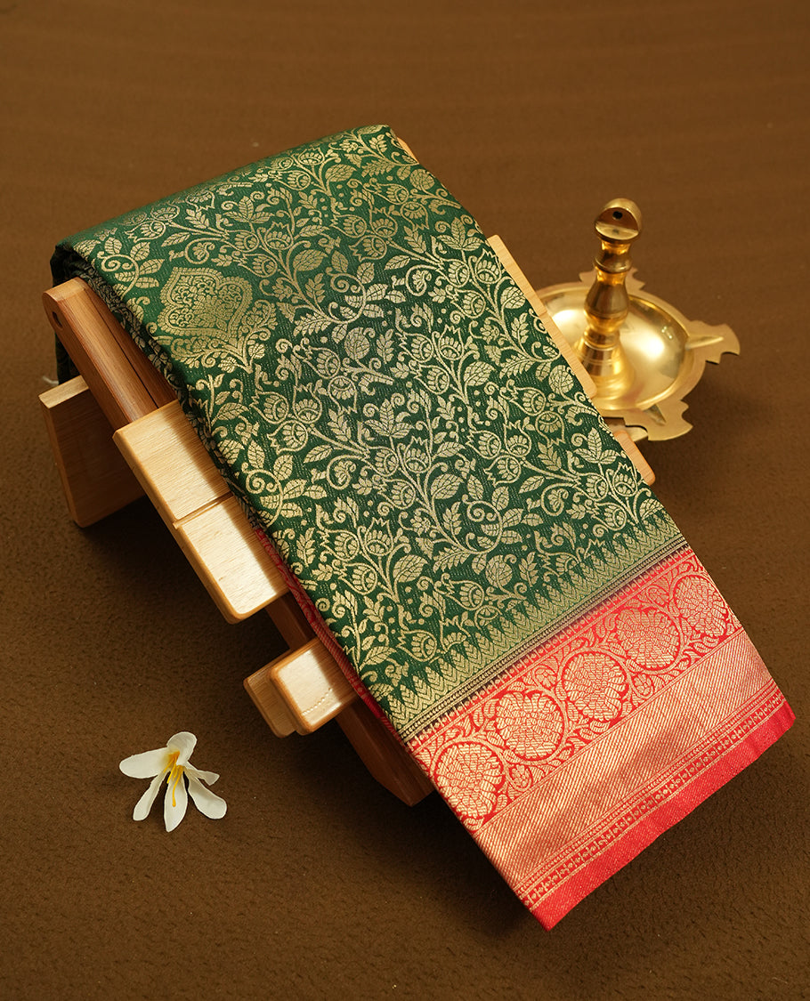 Dark green colour semi silk brocade saree featuring intricate Gold floral kodi patterns across the body, complemented by a contrast rich red colour woven border and pallu, paired with a matching blouse.