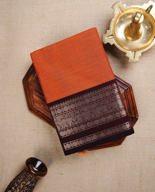 Brick orange colour chettinad cotton saree featuring Elegant plain body, complemented by contrast Black colour with Gold zari border, paired with matching blouse piece.
