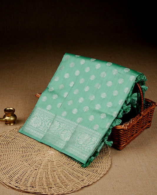Light green colour banaras saree featuring silver zari buttas on body, complemented silver zari on self colour border, comes with matching blouse piece.