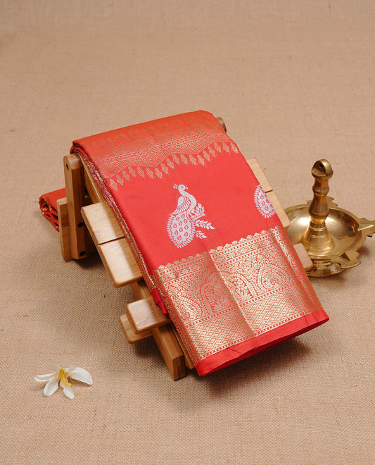 Red colour semi wedding silk saree featuring Gold zari pattern on body, complemented Silver Peacock motifs & gold zari border, paired with matching blouse piece.