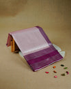 Baby pink colour semi silk saree featuring Silver zari Floral kodi pattern on body, complemented by contrast purple colour with silver zari border, comes with matching blouse piece.