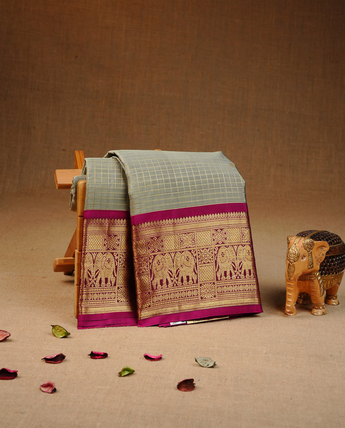 Greenish grey colour traditional kancheepuram silk saree featuring Gold zari check with buttas on body, complemented by contrast magenta colour with matching blouse piece.