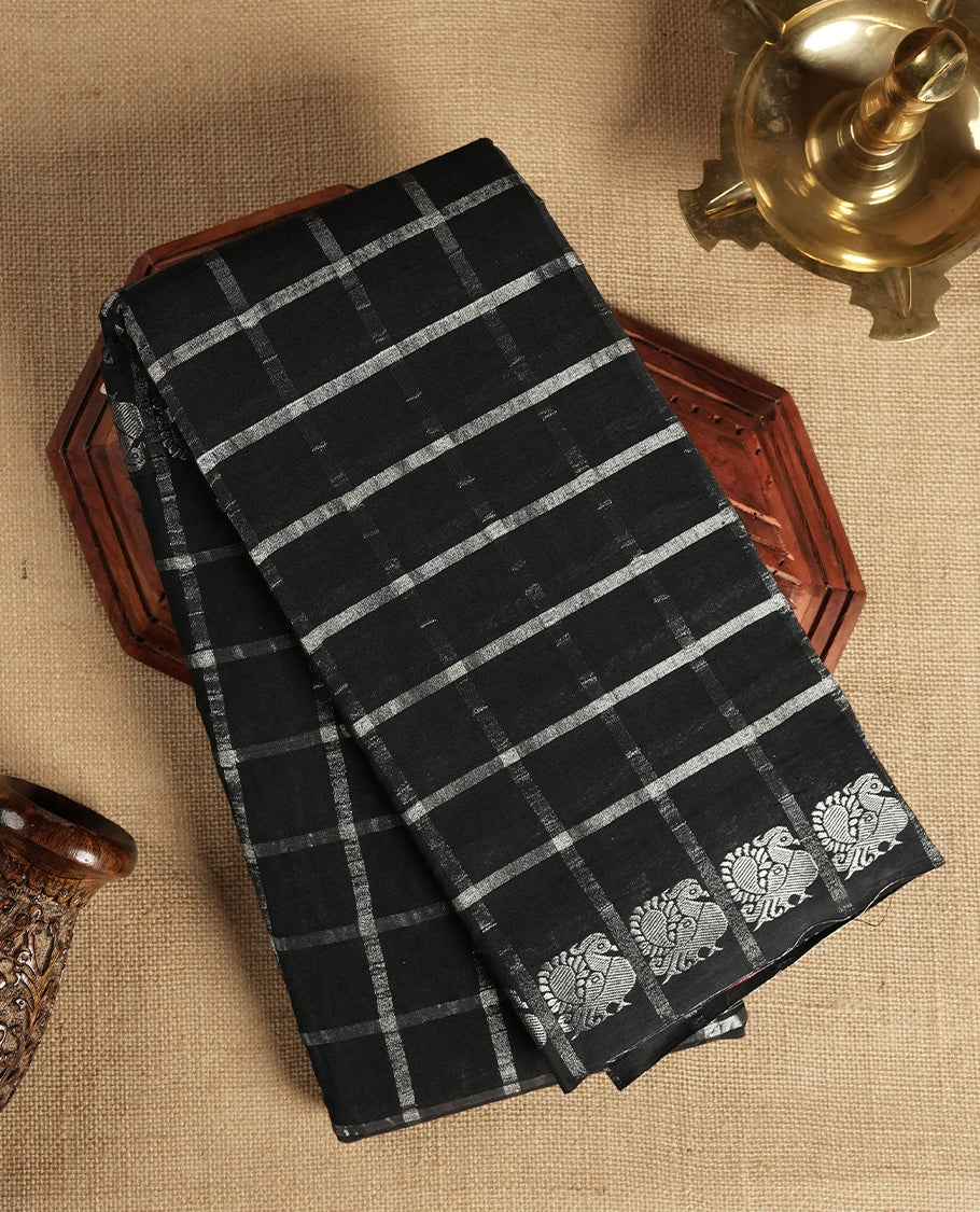 Black colour Chettinad cotton saree featuring silver checked patterns on the body, accentuated with elegant silver peacock motifs along the border & Comes with a matching blouse piece.