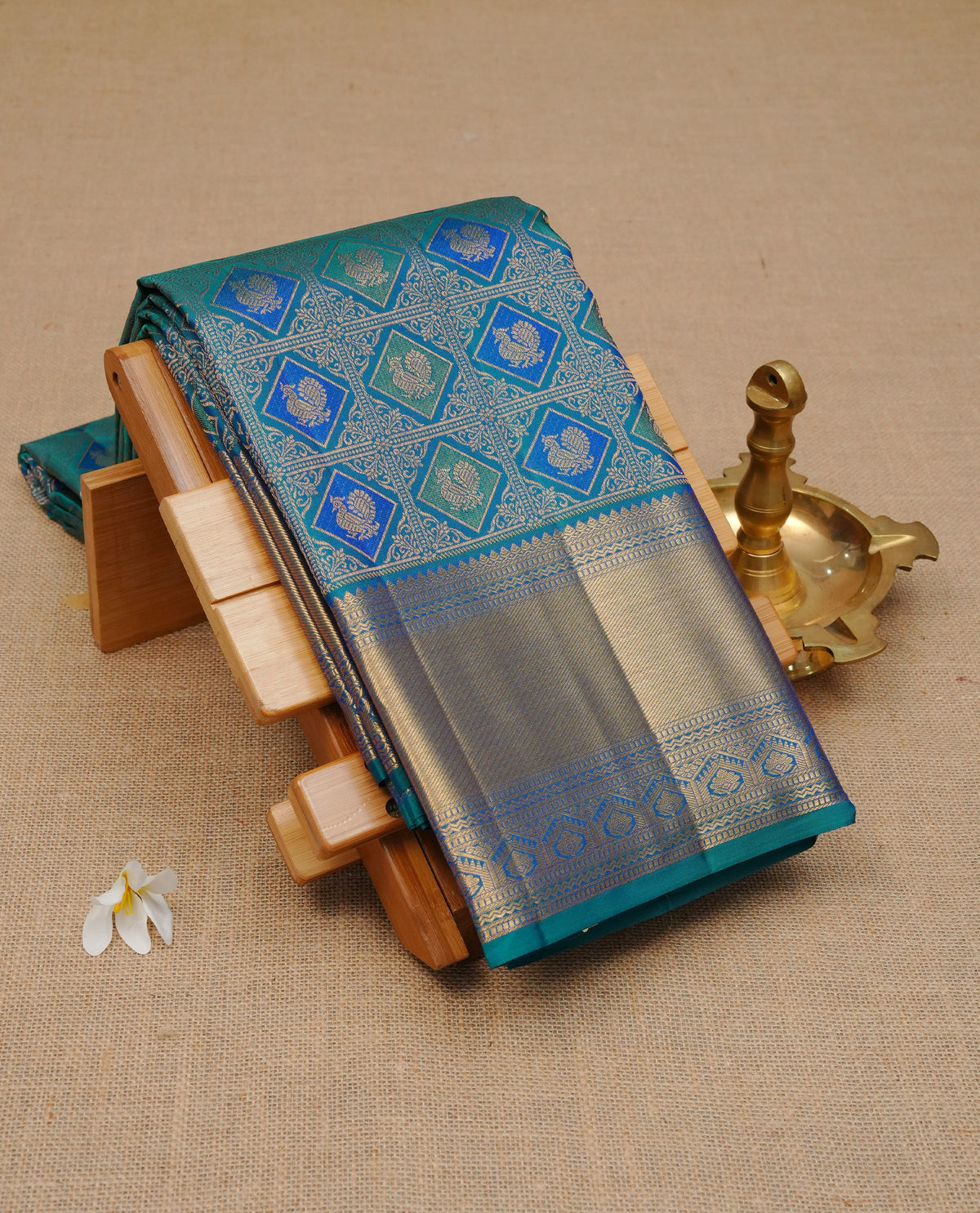 Peacock colour pure wedding silk saree featuring Gold zari inside box diamond with peacock motifs pattern on body, complemented by self colour with traditional border, comes with matching blouse piece.