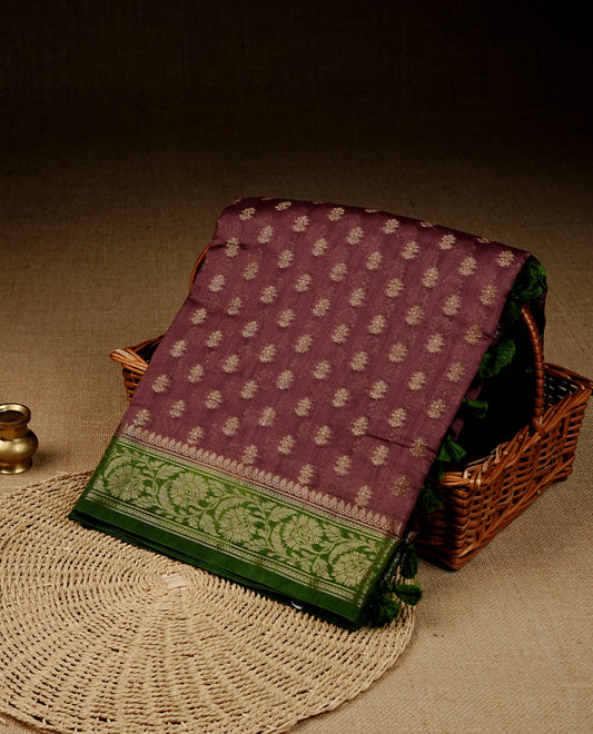 Brown colour Banaras silk saree featuring gold zari buttas on body, complemented by contrast Green colour border, comes with matching blouse piece.