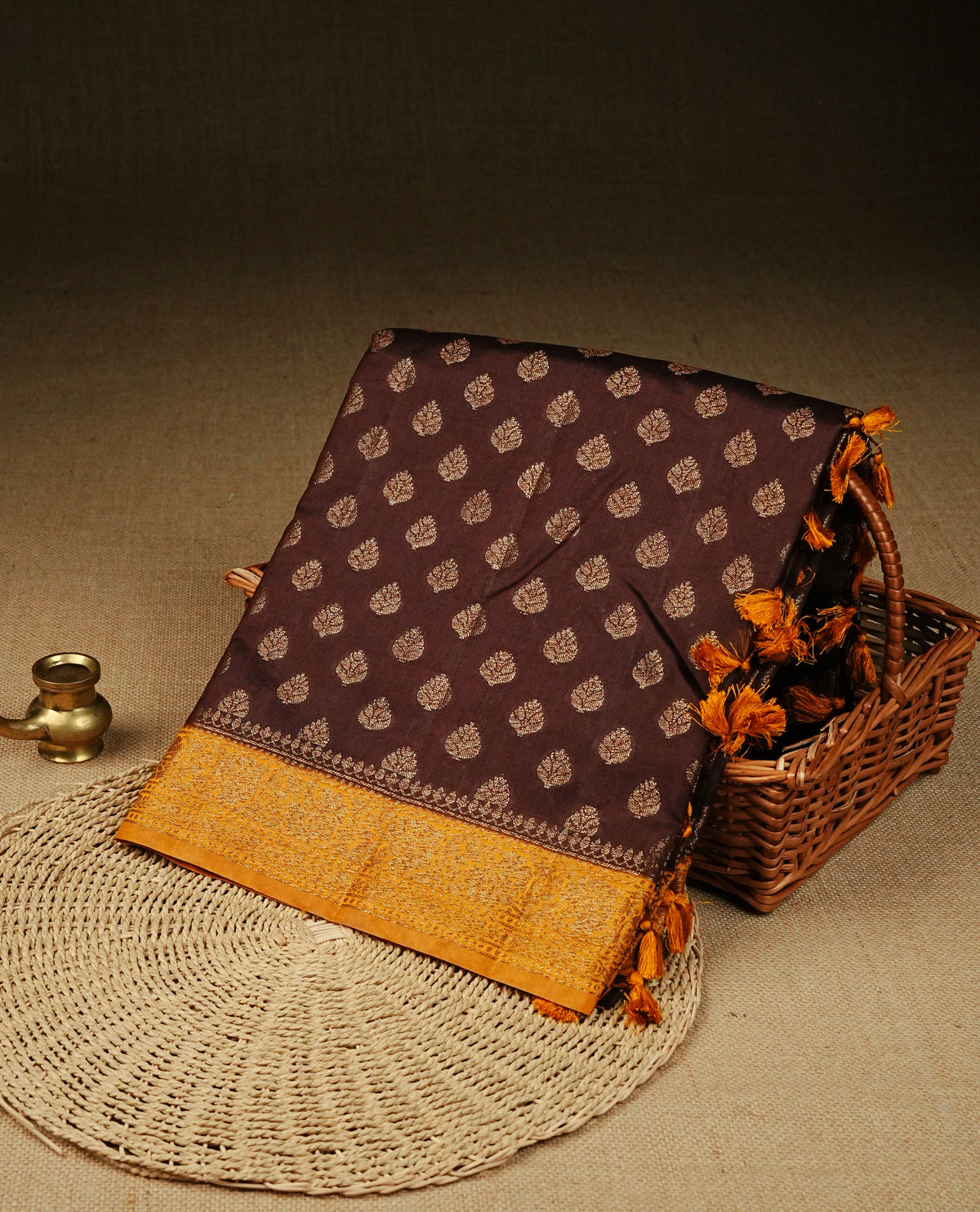 Chocolate colour banaras saree featuring Gold zari buttas on body, complemented by contrast mustard colour with simple zari border, comes with matching blouse piece.