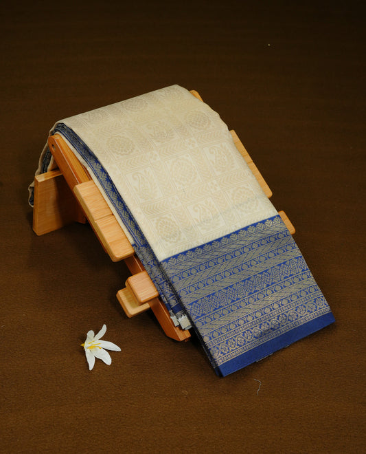 Cream Colour Semi Soft Silk Saree Featuring Gold zari Check With motifs Pattern On Body, Highlighted  by contrast Blue border with Gold zari, paired with matching blouse piece.