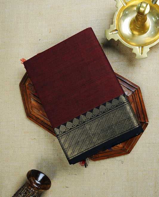 Maroon  colour chettinad cotton saree featuring  Plain body, complemented by  Black Colour With Gold Zari border, paired with matching blouse piece.