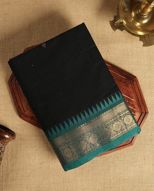 Black colour Chettinad cotton saree accentuated with a rich teal green zari border featuring intricate traditional motifs, The bold temple design enhances its ethnic charm & Comes with a matching blouse piece.
