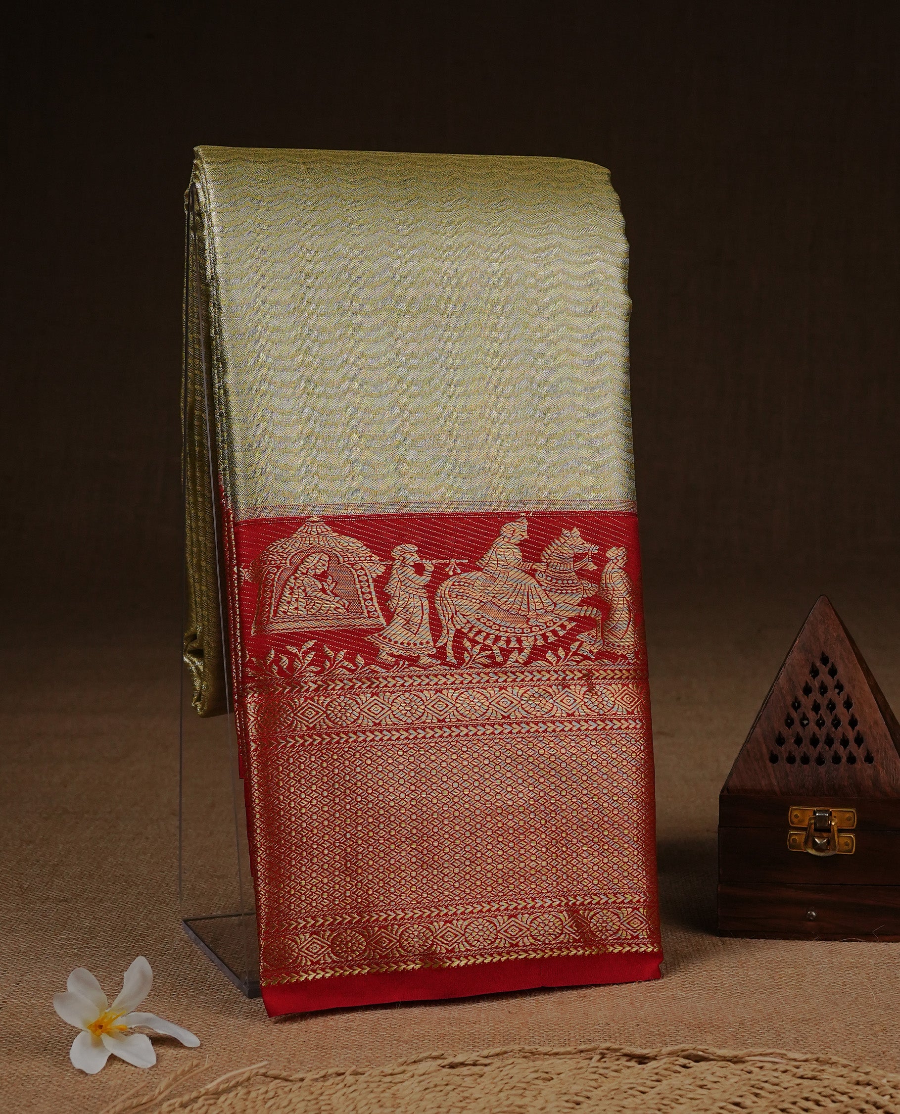 Gold colour Semi Tissue silk saree featuring silver zari pattern on body, complemented by traditional border with contrast Red colour, paired with matching blouse piece.