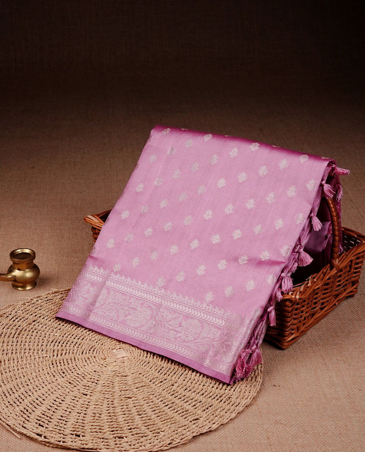Light pink colour banaras saree featuring silver zari buttas on body, complemented silver zari on self colour border, comes with matching blouse piece.