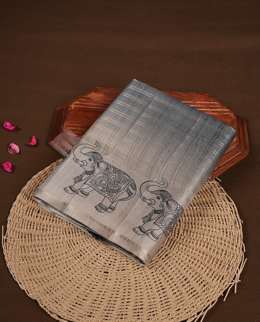 Gray colour semi tusser silk saree featuring Gold zari check pattern across body, faded contrast cream colour border with elephant print and paired with matching blouse.