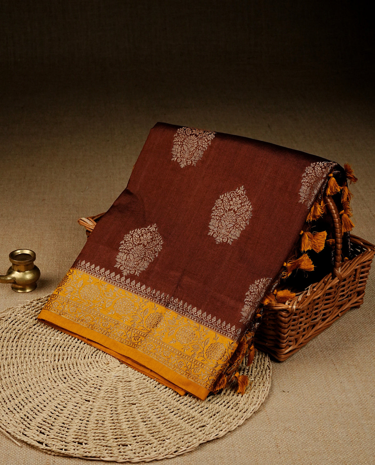 Chocolate colour banaras saree featuring gold zari motifs on body, complemented by contrast Mustard colour with gold zari border, comes with matching blouse piece.