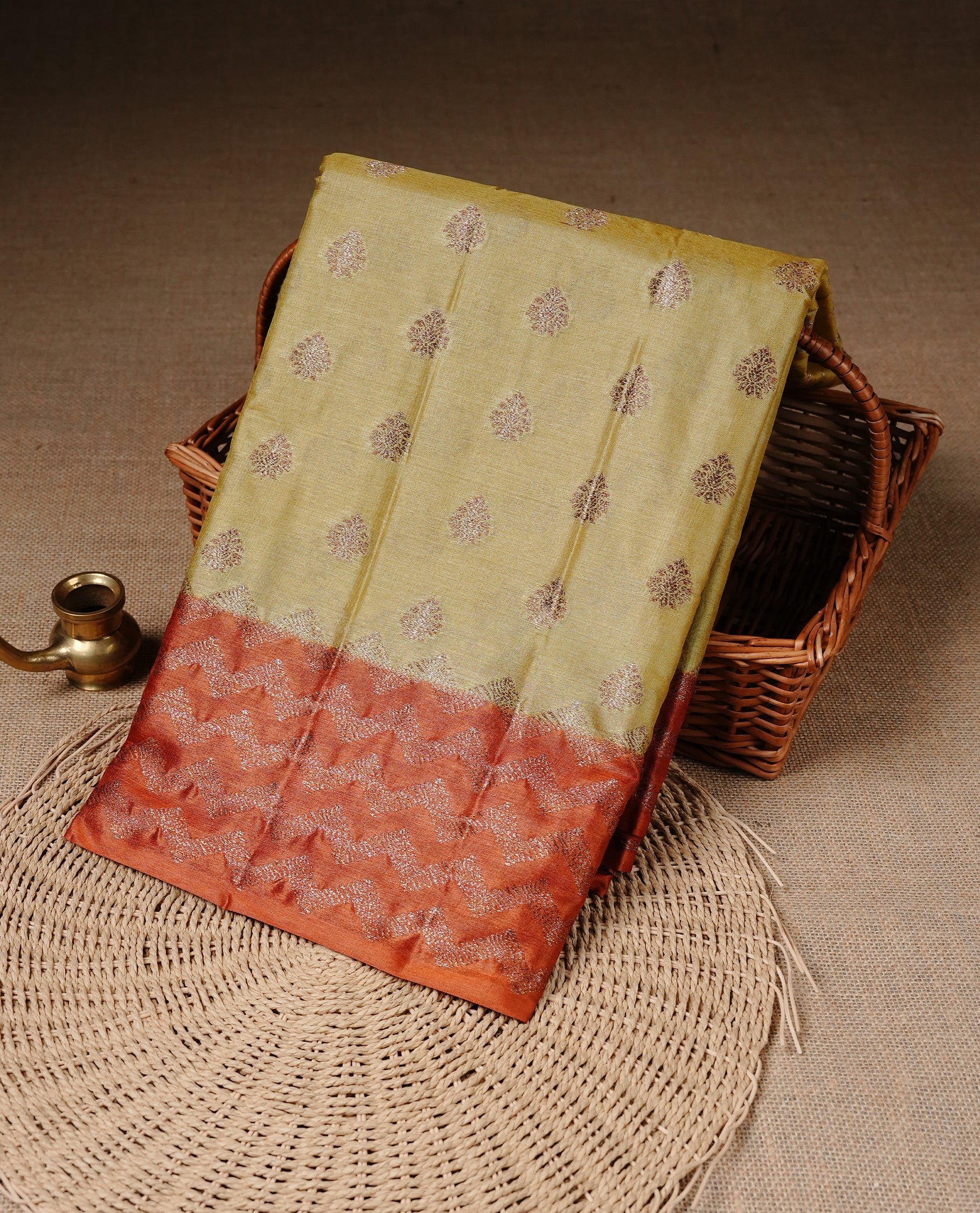 Pale Yellow Colour Tussar silk saree featuring Antique Zari motifs on body, Finished with contrast Orange colour Zigzag zari pattern border, paired with matching blouse piece.