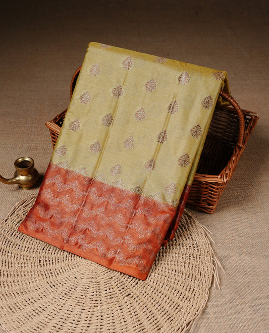 Pale Yellow Colour Tussar silk saree featuring Antique Zari motifs on body, Finished with contrast Orange colour Zigzag zari pattern border, paired with matching blouse piece.
