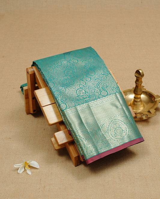 Green colour semi wedding silk saree featuring Gold zari floral kodi pattern on body, complemented by Traditional zari on self colour with Maroon piping, paired with matching blouse piece.