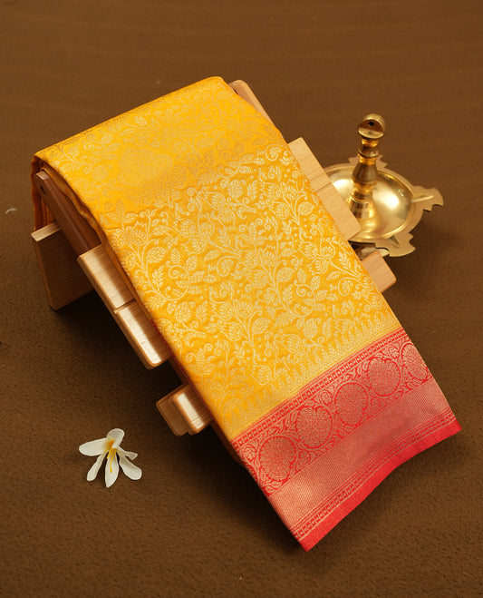Yellow colour semi silk brocade saree featuring intricate Gold Floral kodi patterns across the body, complemented by a Contrast red colour woven border and pallu, paired with a matching blouse.