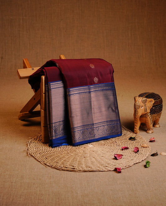 Maroon Colour Traditional Kancheepuram Silk Saree Featuring Gold Zari Floral Motifs on the Body, Complemented by a Contrast Blue Colour  Copper Zari Traditional Border and Pallu, Paired with a Matching Blouse .