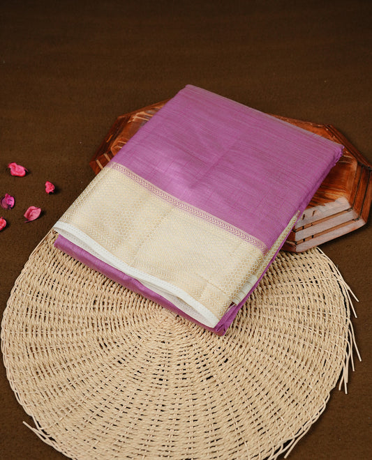 Pink colour Semi Tussar silk saree featuring an elegant plain body, accentuated by a contrast cream border adorned with intricate gold zari work, paired with a matching blouse piece.