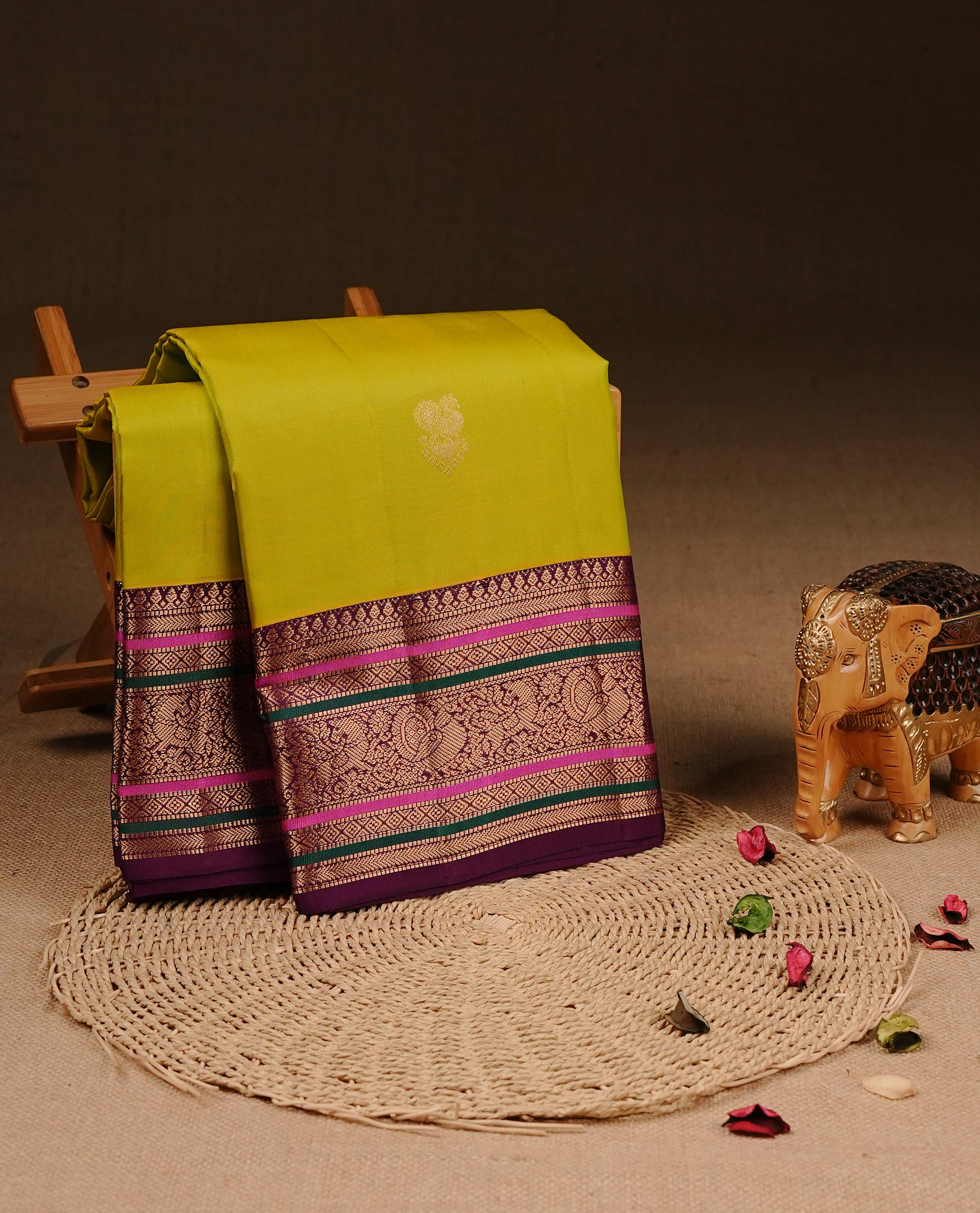 Olive colour Traditional Kancheepuram silk saree featuring gold zari motifs on body, enhanced with contrast Purple with multicolour & traditional border, paired with matching blouse piece.
