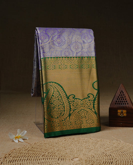 Light purple colour tissue saree featuring silver & gold zari floral kodi pattern on the body, highlighted by a contrast Green colour border with gold traditional zari, paired with a matching blouse piece.
