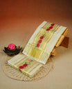 Cream Colour  tissue set mundu featuring a subtle checked body, enhanced with elegant red floral motifs & a rich gold zari kara