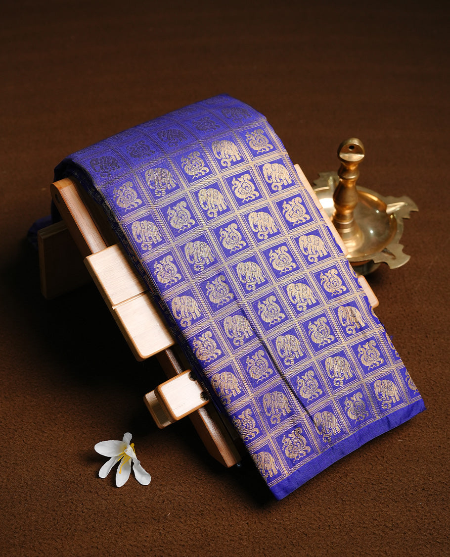 Navy Blue colour semi wedding saree featuring gold zari elephant & peacock motif on check pattern on body, complemented by self colour with traditional border, paired with matching blouse piece.
