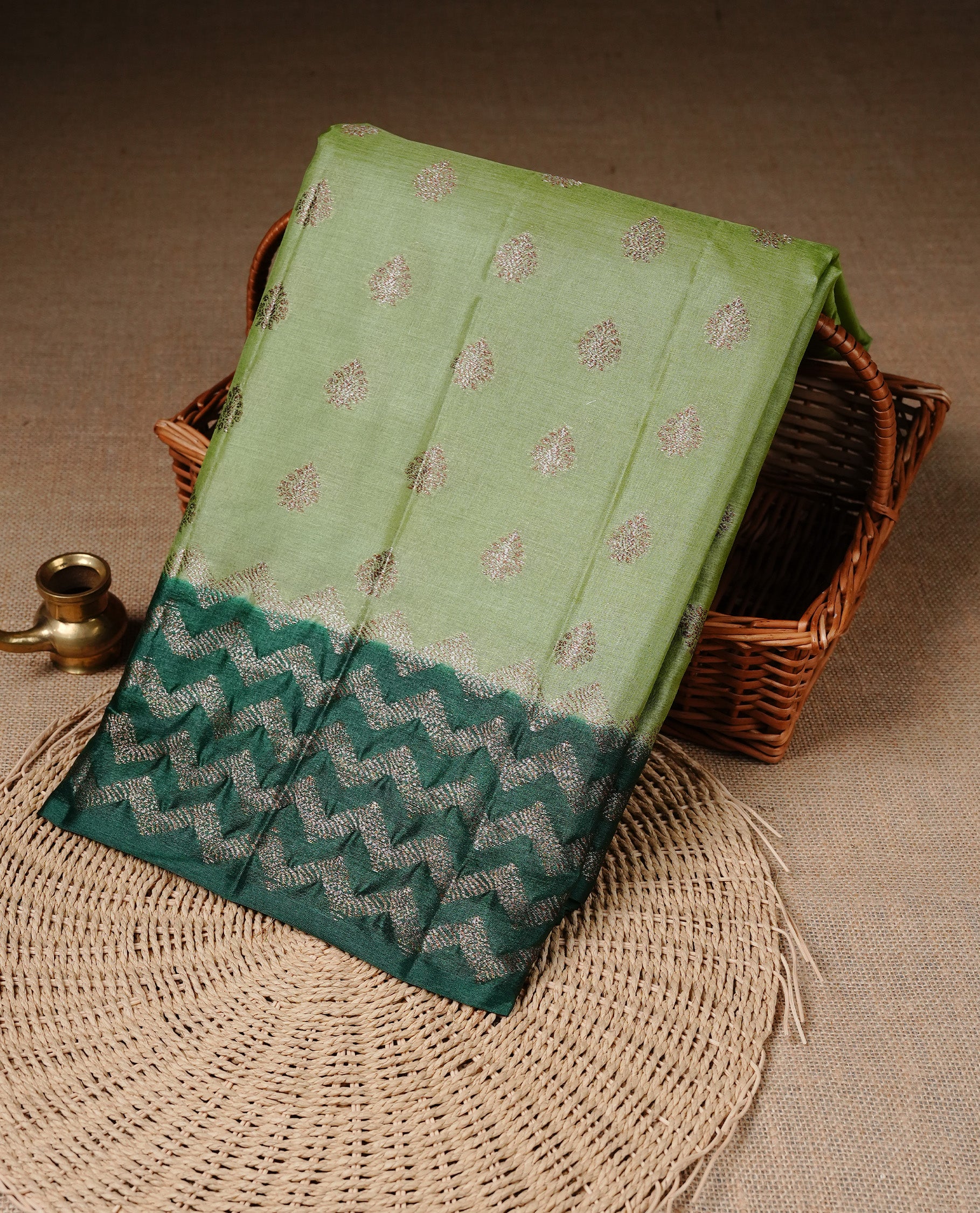 Pastel Green Colour Tussar silk saree featuring Antique Zari motifs on body, Finished with contrast Green colour Zigzag zari pattern border, paired with matching blouse piece.