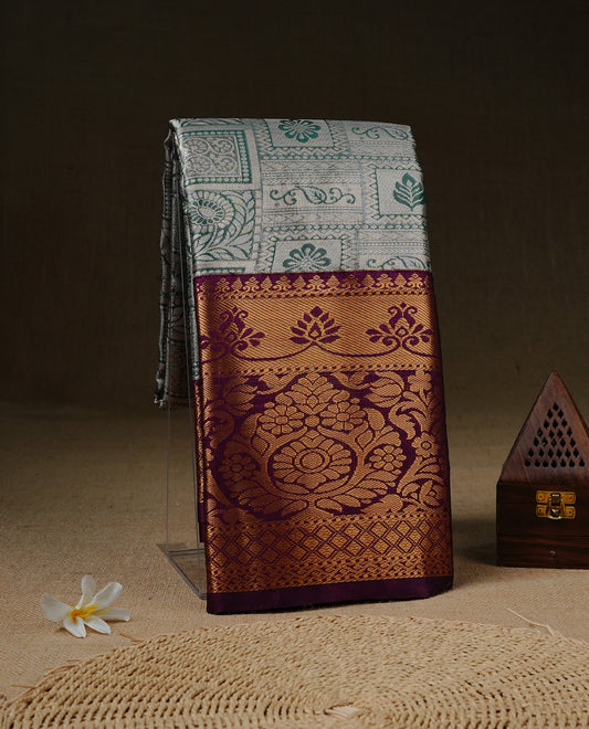 Light green colour tissue saree featuring silver & gold zari floral kodi pattern on the body, highlighted by a contrast Burgundy colour border with gold traditional zari, paired with a matching blouse piece.
