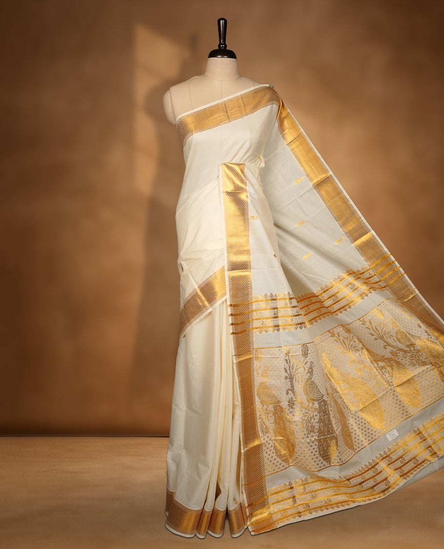 Elegant off white colour cotton Kerala saree with gold zari buttas, broad kasavu border, and richly woven traditional pallu, paired with a matching blouse