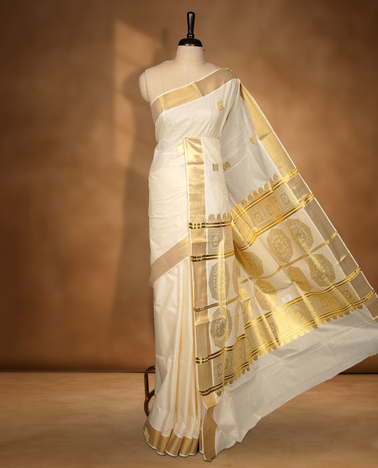 Elegant Off white colour cotton Kerala saree with gold zari buttas, broad kasavu border, and richly woven traditional pallu, paired with a matching blouse