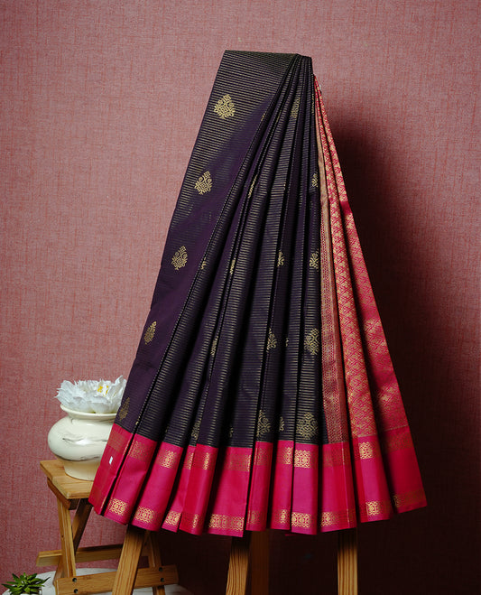 Deep purple coloured soft silk saree featuring gold zari stripes and motifs across the body, enhanced with a contrast Magenta border and pallu, paired with a matching contrast blouse piece.