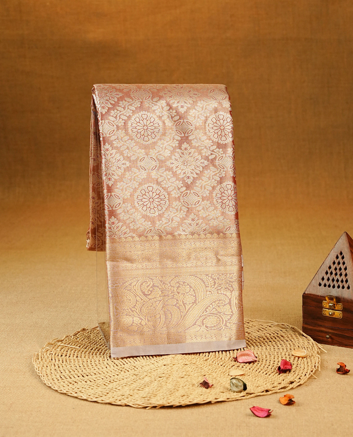 Pastel Red colour Semi Tissue Silk Saree featuring gold zari Works on the body, complemented by an intricately woven gold zari pallu, a rich baby pink border with gold zari work and paired with a matching plain blouse piece.