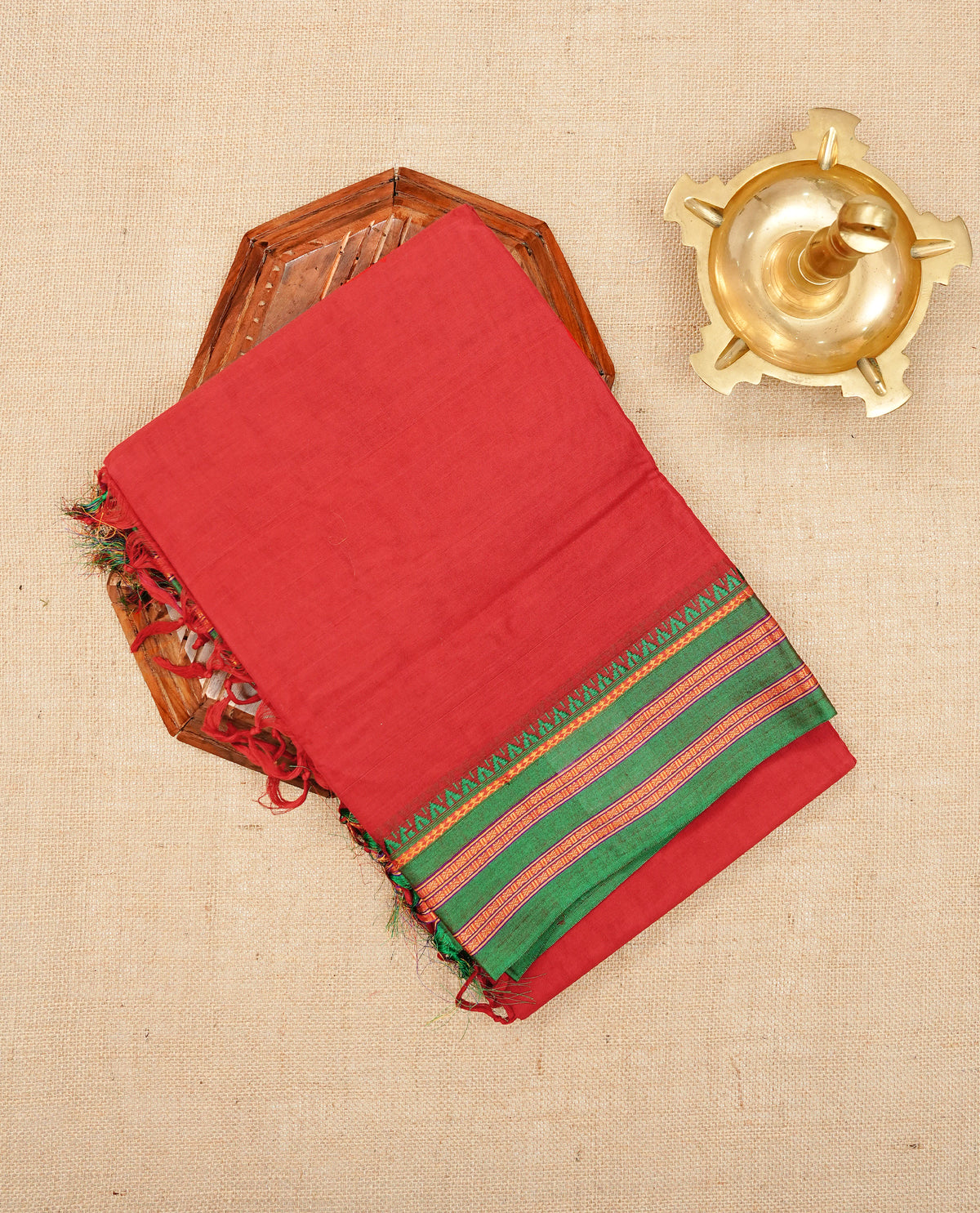 Red colour Narayanapattu cotton saree with a plain body, complemented by a Green Colour with border with elegant gold zari  & green colour temple designed detailing and a contrast striped pallu, paired with a matching blouse piece.
