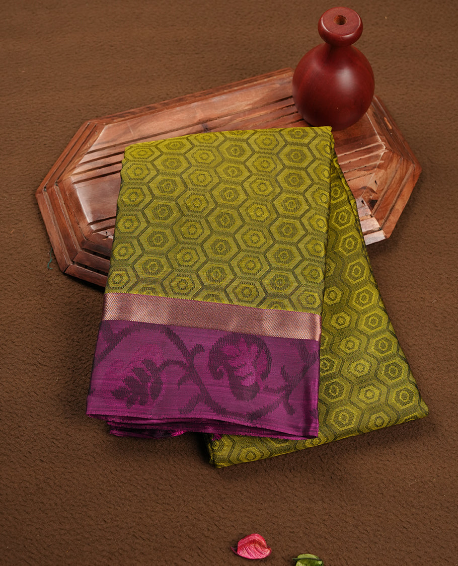 Olive green colour soft silk saree featuring Antique zari geometric motifs on the body, complemented by a contrast Purple zari border and pallu, paired with a matching blouse piece.