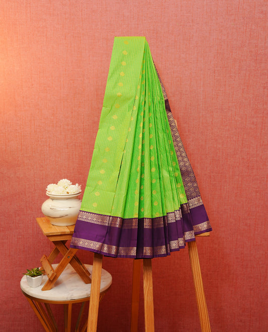 Light green colour soft silk saree featuring gold zari checks & motifs on body, contrast purple colour traditional border, grand pallu comes with matching blouse piece.