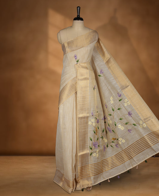 Beige colour Banarasi linen silk saree featuring hand brushed colour with Floral  & birds printed pattern on body, gold zari woven geometric design border with self colour pallu and comes with a matching blouse