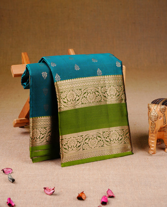 Teal Blue colour Traditional Kancheepuram Silk Saree with Elegant Gold Zari Buttas on the Body, Enhanced with a Contrast Green Colour  with Gold Zari Border and Rich Pallu, Paired with a Matching Blouse Piece.