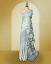Sky Blue colour semi tussar saree adorned with elegant white applique work in leaf and floral designs across the body and border, paired with a matching blouse.