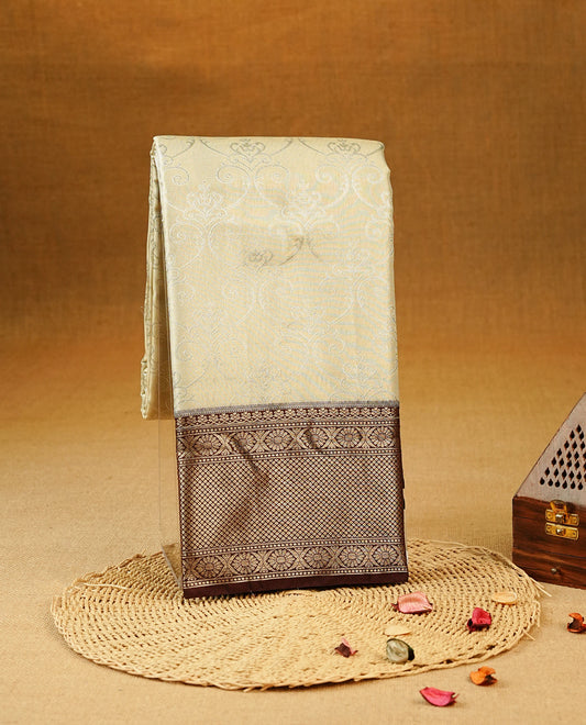 Beige Colour Tissue Silk Saree featuring an elegant Silver zari woven body, a richly woven Gold zari pallu, complemented by a Dark Brown With Gold zari border and paired with a Matching  blouse piece.