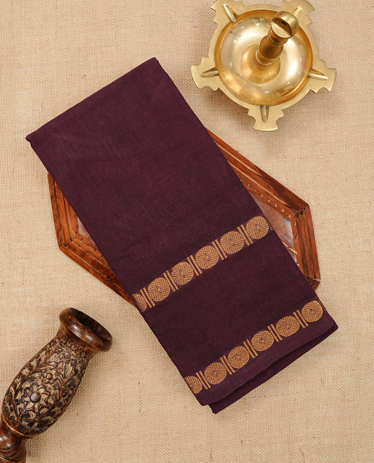Dark Wine Colour  Sungudi Cotton Saree with gold zari motifs on the body, a matching gold zari border, and a plain pallu. Paired with a contrast Reddish Pink colour  blouse piece  featuring a gold zari peacock border.