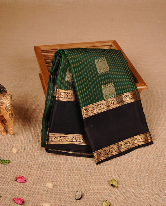 Green colour traditional kancheepuram silk saree featuring gold zari stripes & motifs on body, complemeneted by contrast chocolate colour with traditional border, paired with matching blouse piece.
