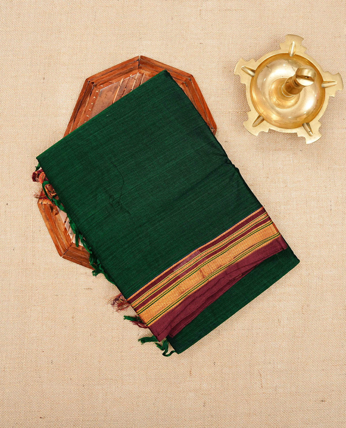 Bottle green colour Narayanapattu cotton saree with a plain body, complemented by a Maroon colour with elegant gold zari detailing border & contrast striped pallu, paired with a matching blouse piece.
