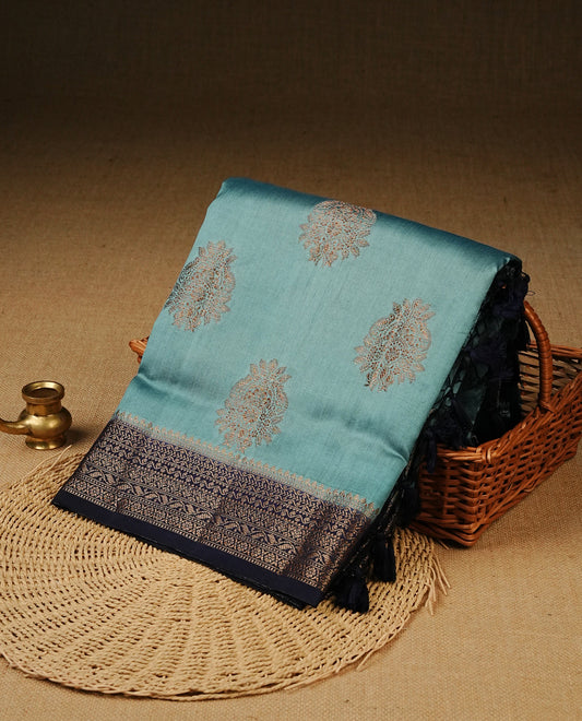 Pastel Aqua Colour Tussar Silk saree with elegant antique zari floral motifs On Body, a contrasting navy blue zari border, a rich zari pallu, Paired With a matching  blouse piece.